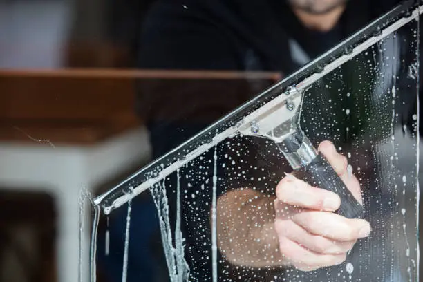 Technician inspecting exterior window buildup on a multi-story home with professional equipment