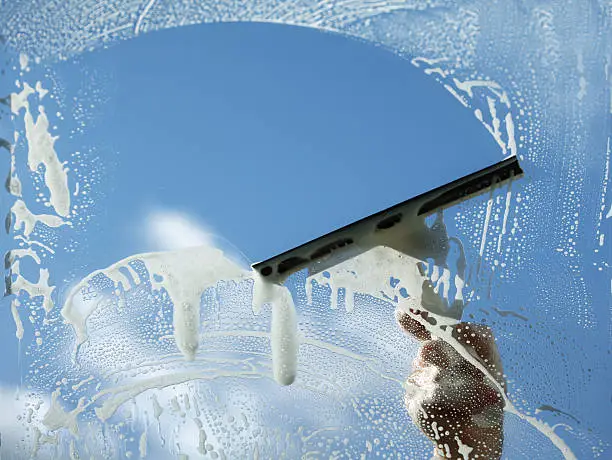 Cleaner wiping large storefront windows before opening hours in a busy Murray retail area
